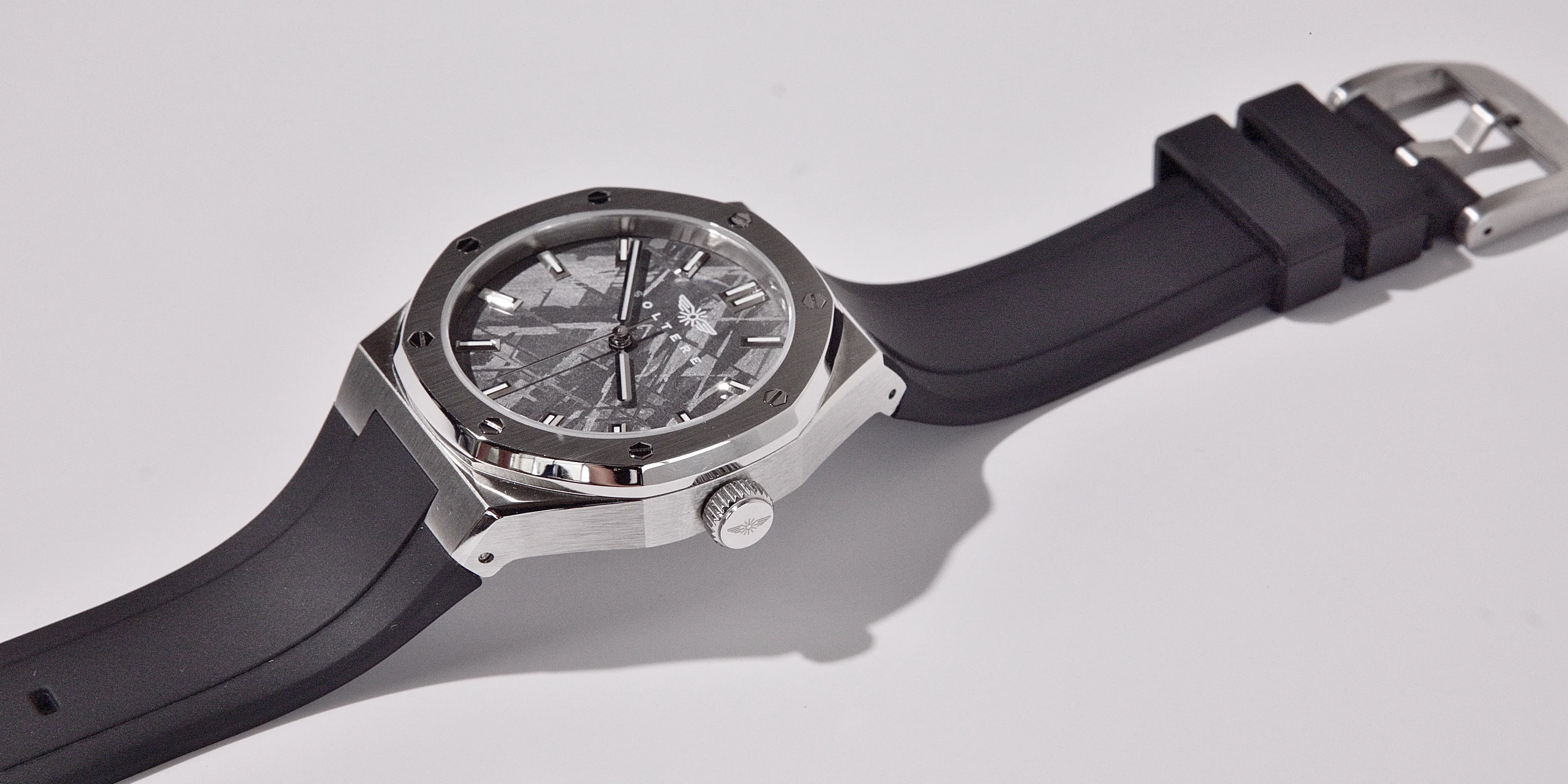 The Soltere Visto lying on a pale grey surface: brushed steel octagonal case, engraved crown, grey meteorite-pattern dial, black rubber strap.